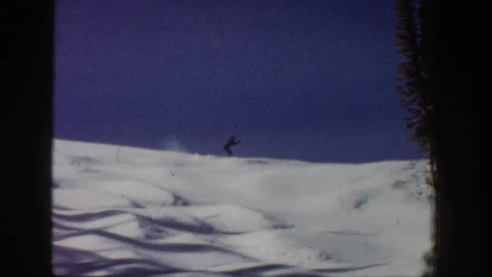 1961 Aspen 8mm frame showing a distant skier crossing a snowy slope beneath a deep blue sky.
