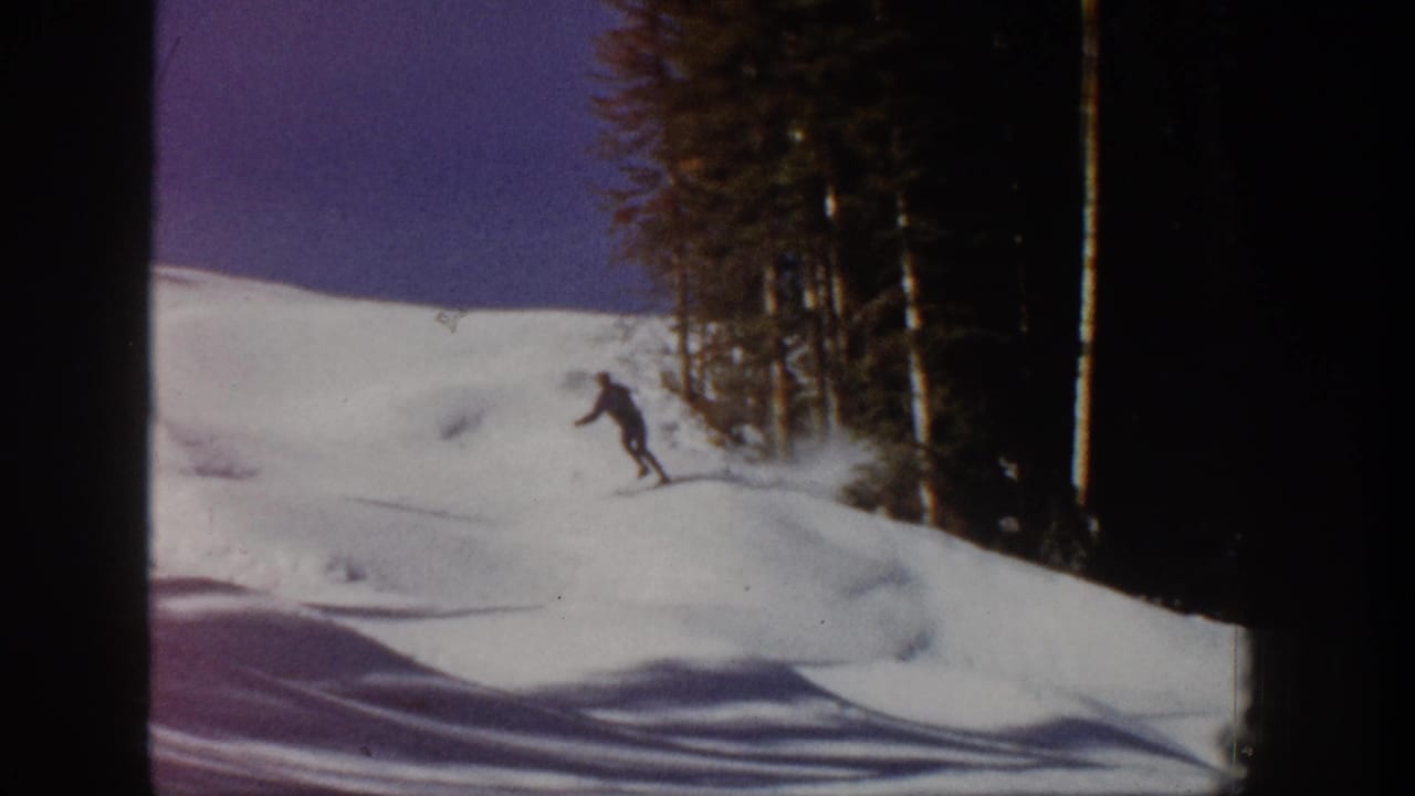 1961 Aspen 8mm frame showing a lone skier on a snow-covered slope near dark evergreen trees.