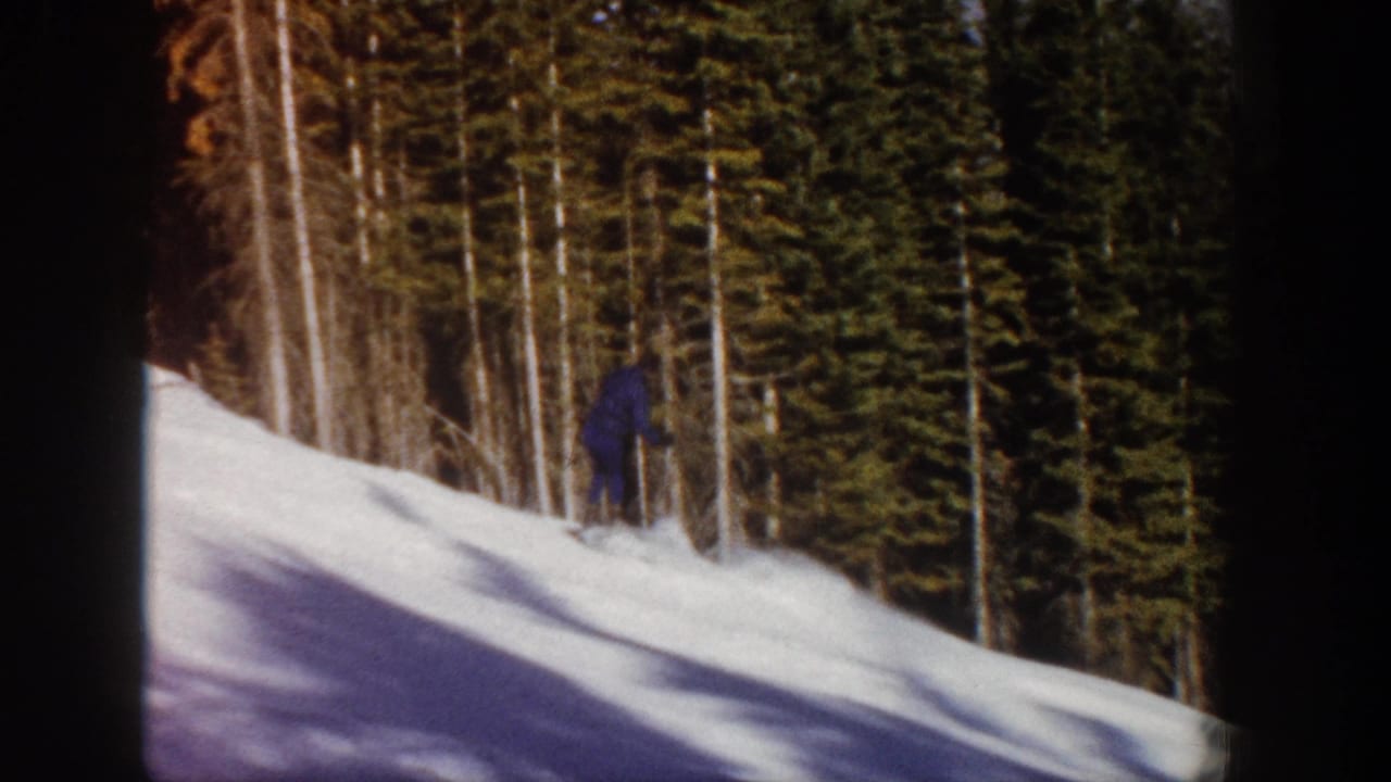 A distant skier in dark clothing moves across an Aspen, Colorado snow slope in 1961 home-movie footage.