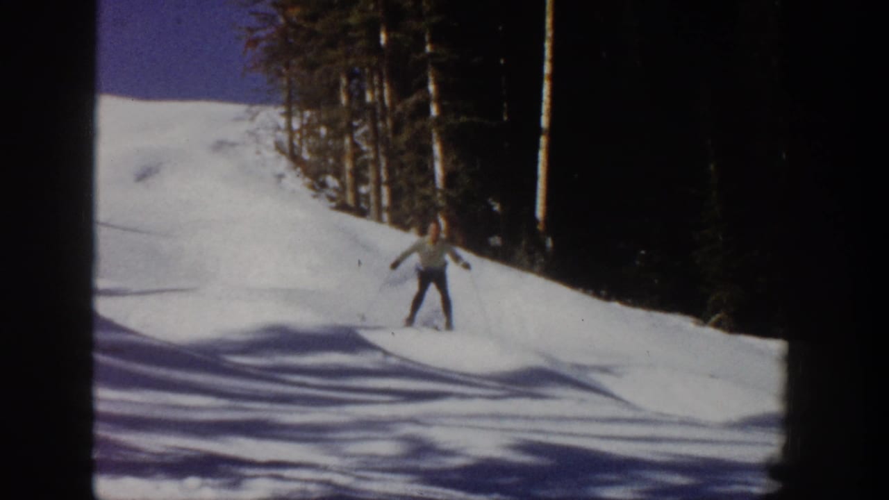 Skier standing or gliding on skis near the edge of a snowy run.
