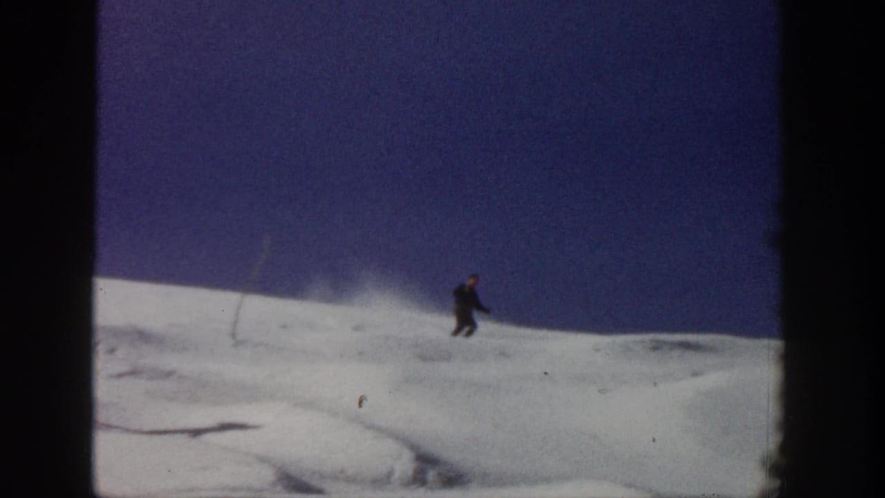 Skier descending across open snow with dark frame borders.