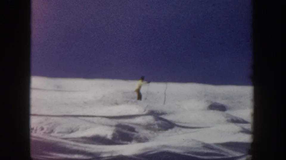 A lone skier descends an open snowy hill in Aspen, Colorado, in 1961-era 8mm footage.