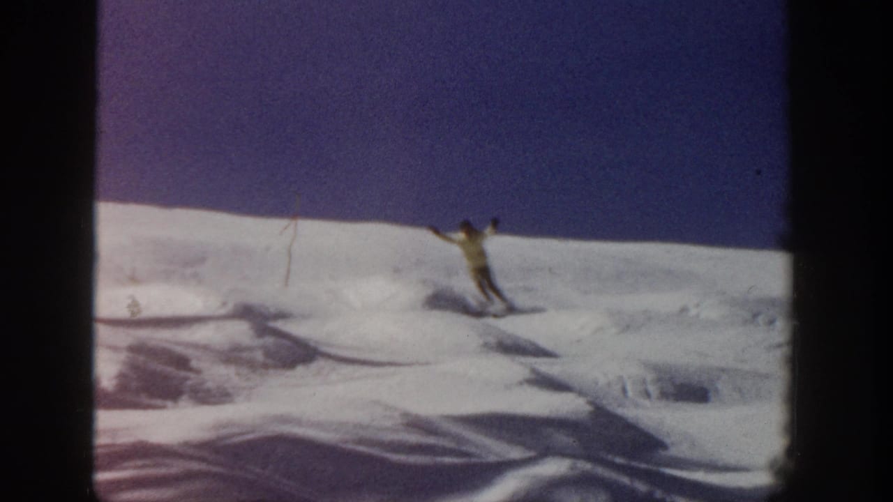 Skier with poles gliding across an open snowfield.