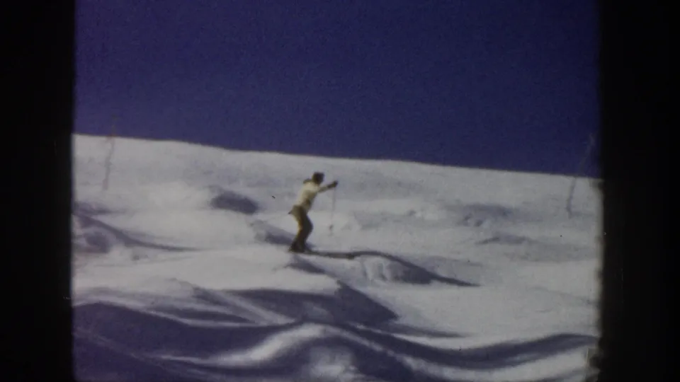 A skier in profile travels over an uneven snow slope in Aspen, Colorado, in 1961 8mm home-movie footage.