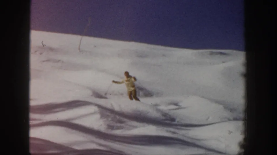 The skier continues downhill across rippled snow in Aspen, Colorado, with 8mm grain and gate edges visible.