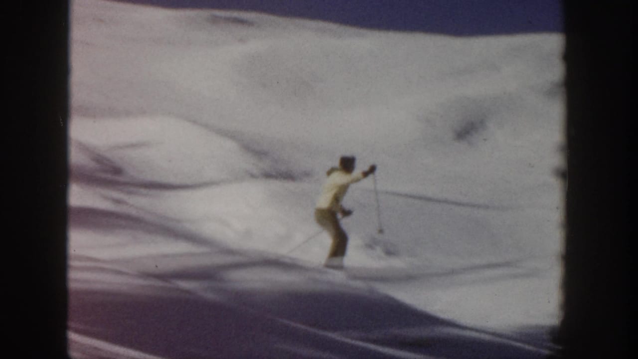 In supported 1961 Aspen footage, a skier in yellow outerwear glides across open snow with long shadows and soft 8mm blur.