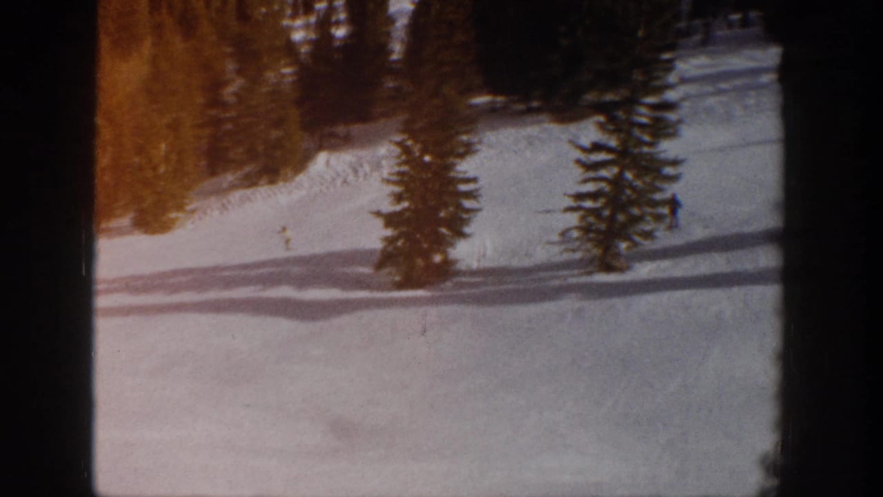Aspen, Colorado 1961 home-movie view of a snow-covered ski slope bordered by evergreens, with distant skiers barely visible.