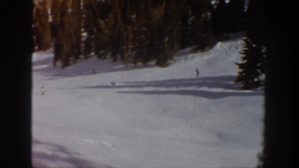 Aspen, Colorado 1961 ski scene with small skiers spread across a bright mountain run beneath dense evergreens.