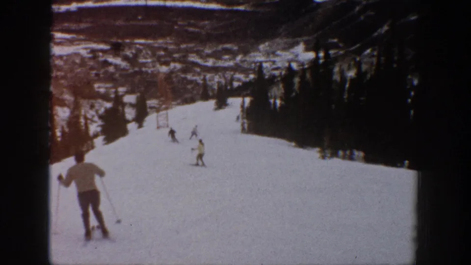 1961 Aspen ski footage frame with a foreground skier moving downhill and several skiers farther down the slope.