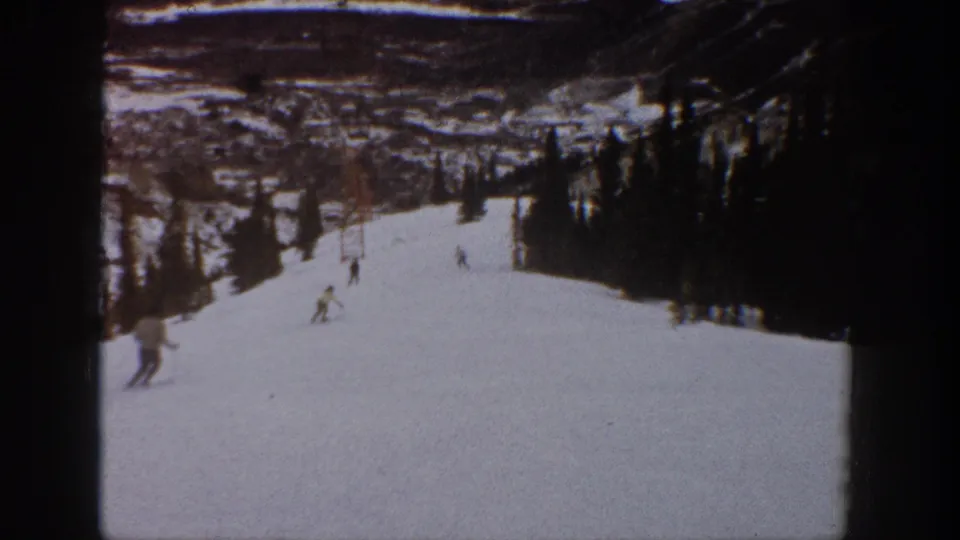 1961 Aspen frame showing multiple skiers spread across a snowy mountain run, viewed from an amateur 8mm camera position.