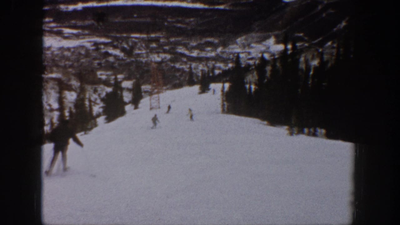 Several skiers are spread across a snowy downhill run near lift towers.