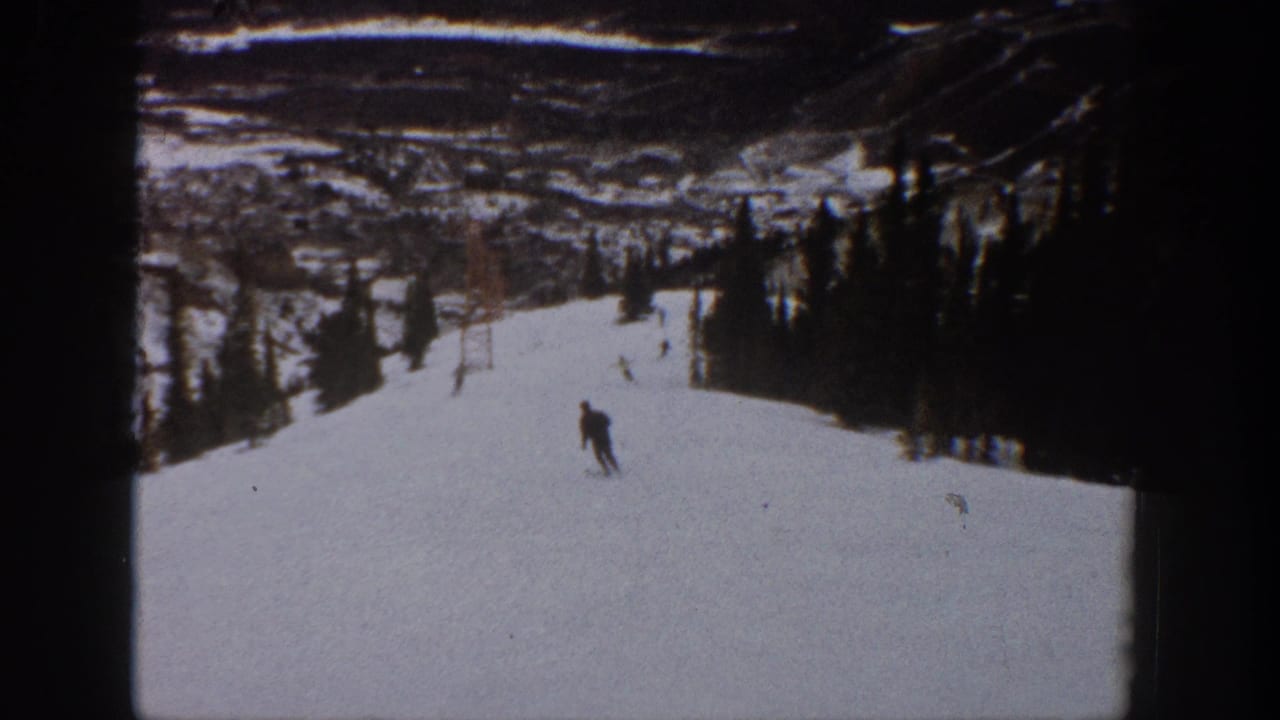 A lone skier moves down a snowy Aspen, Colorado slope in 1961, with trees and distant mountain terrain in soft 8mm color.