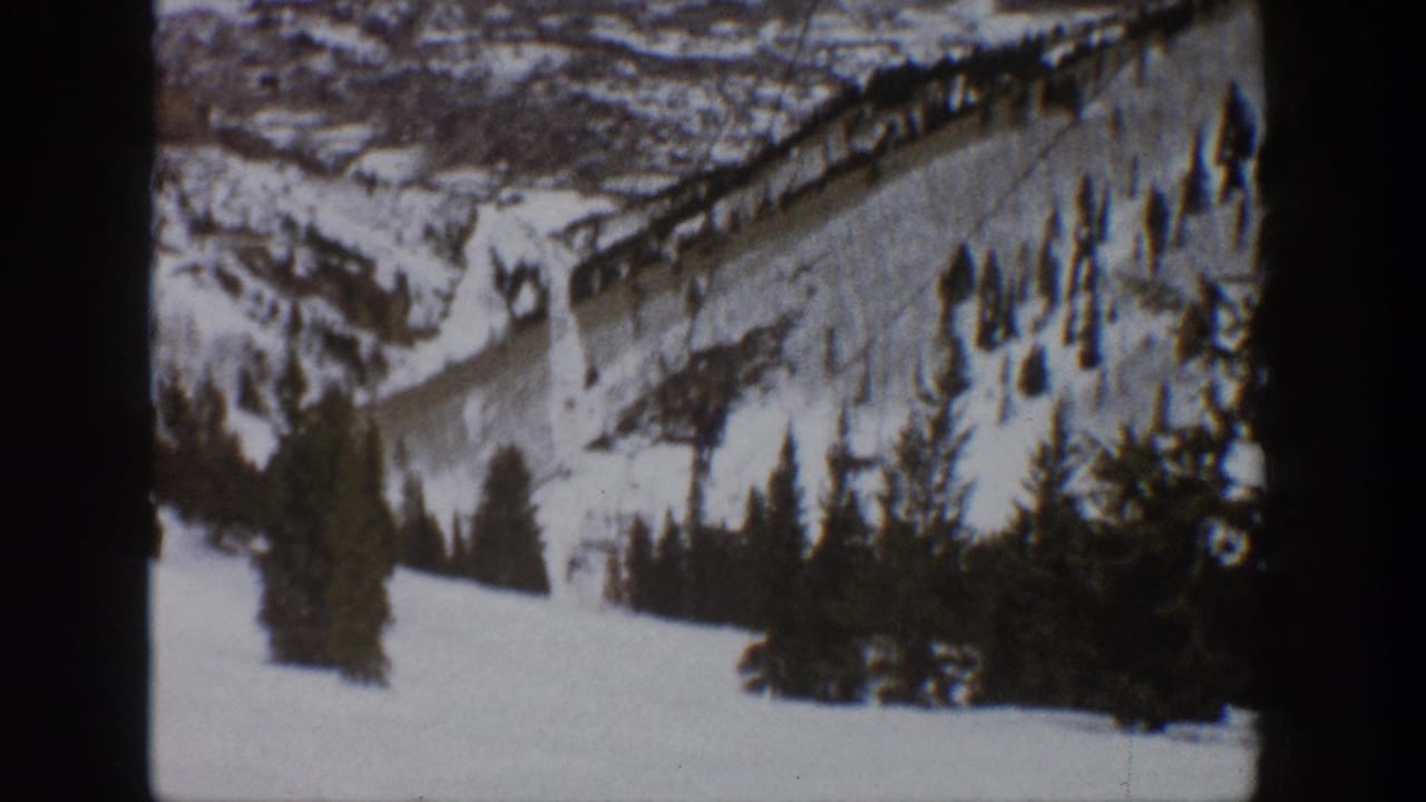 Vintage Aspen winter frame with a lift line ascending a snow-covered hillside above dark evergreen trees.