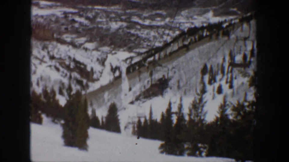 Aspen winter resort landscape from 1961, showing a ski lift line across a snowy slope and trees in the foreground.