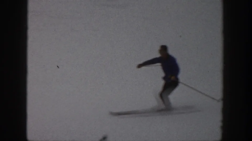 Home-movie frame from Aspen showing the skier shifting weight during a turn on a bright snow surface.