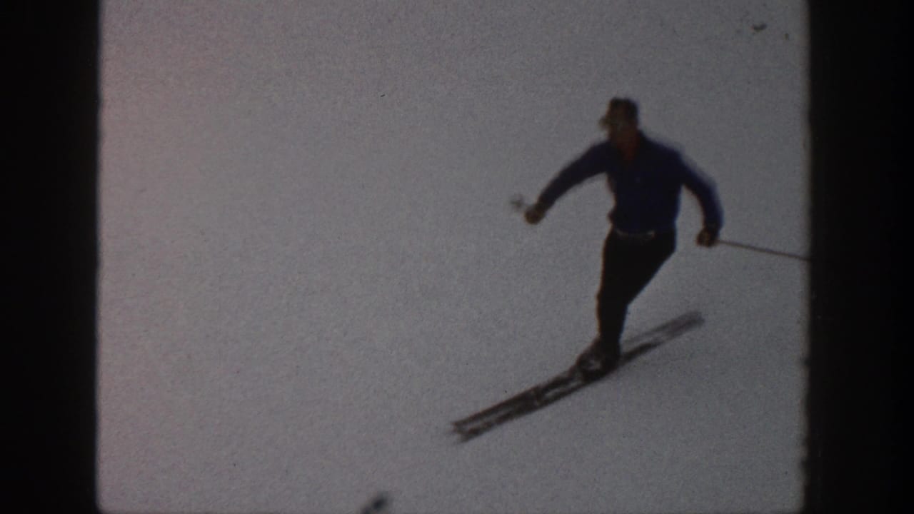 In 1961 Aspen home-movie footage, a man in a blue sweater and dark pants skis across a pale snowy slope.