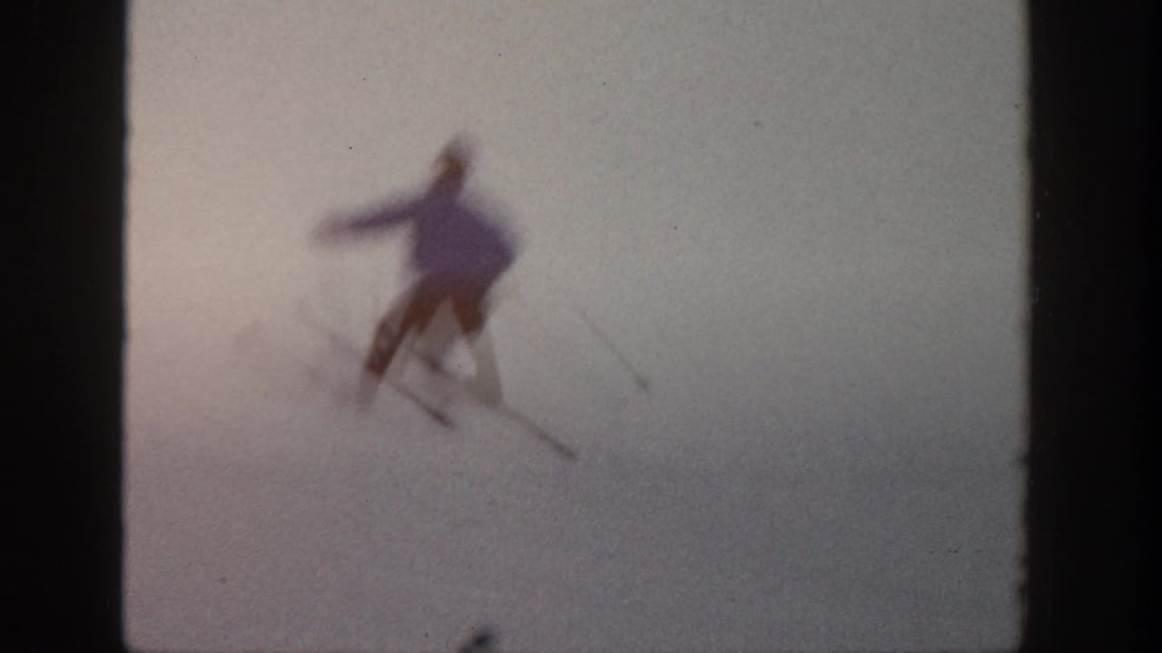 A blurred skier turns on a snowy slope with poles visible.