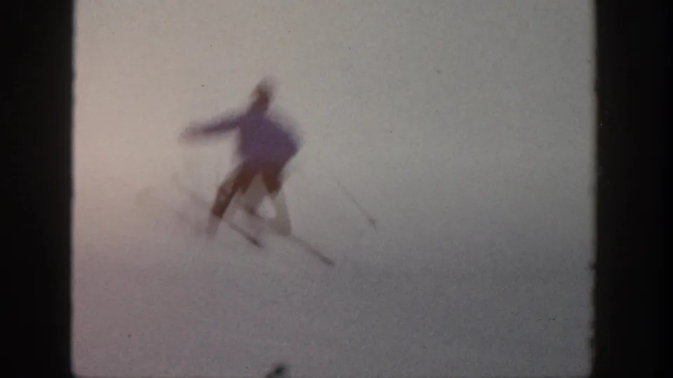The Aspen skier appears blurred in motion while turning on snow, with skis and poles faintly visible in the 8mm frame.