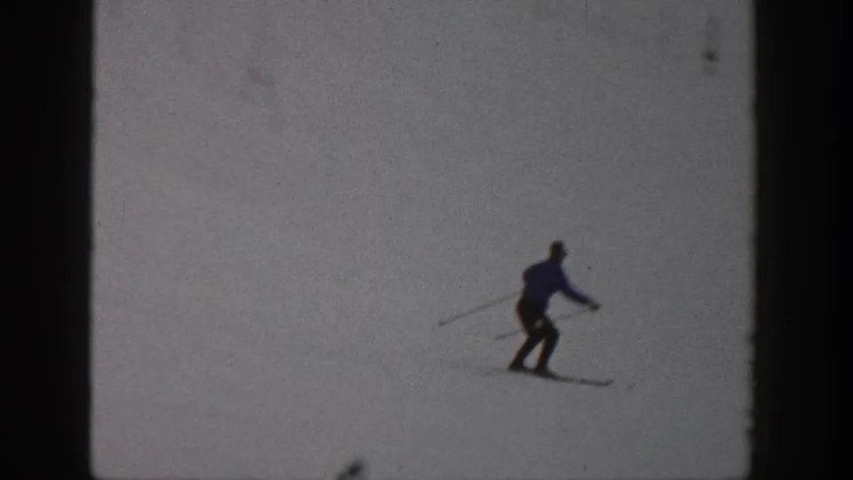 A distant skier in dark winter clothing moves across a snowy Aspen slope in 1961 home-movie footage.