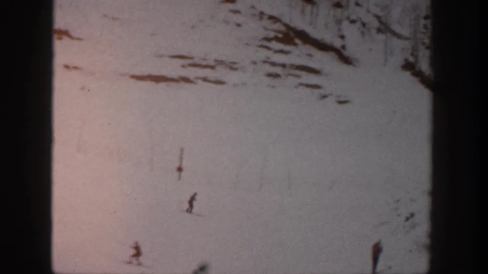 Multiple small skiers are visible on the Aspen slope, seen through faded 8mm color, grain, scratches, and heavy frame borders.