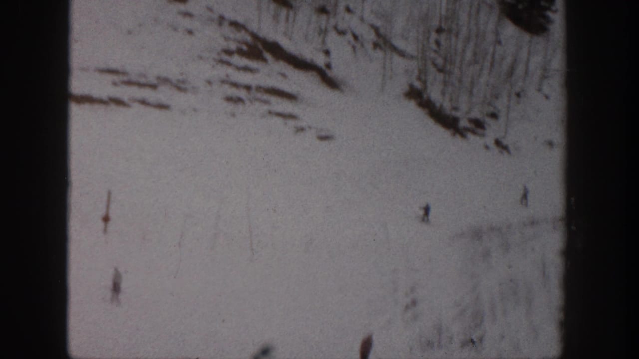 Distant skiers move down a snow-covered Aspen slope in soft 8mm color footage from 1961.