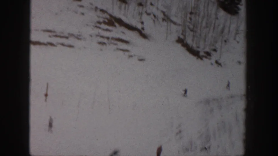Distant skiers move down a snow-covered Aspen slope in soft 8mm color footage from 1961.