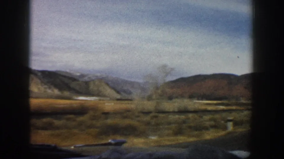 1961 8mm home-movie view of Colorado valley terrain and distant hills through a moving car window.