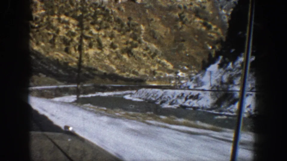 The Aspen-area mountain drive continues past roadside snow, trees, and rock slopes, with the car interior framing the 8mm view.