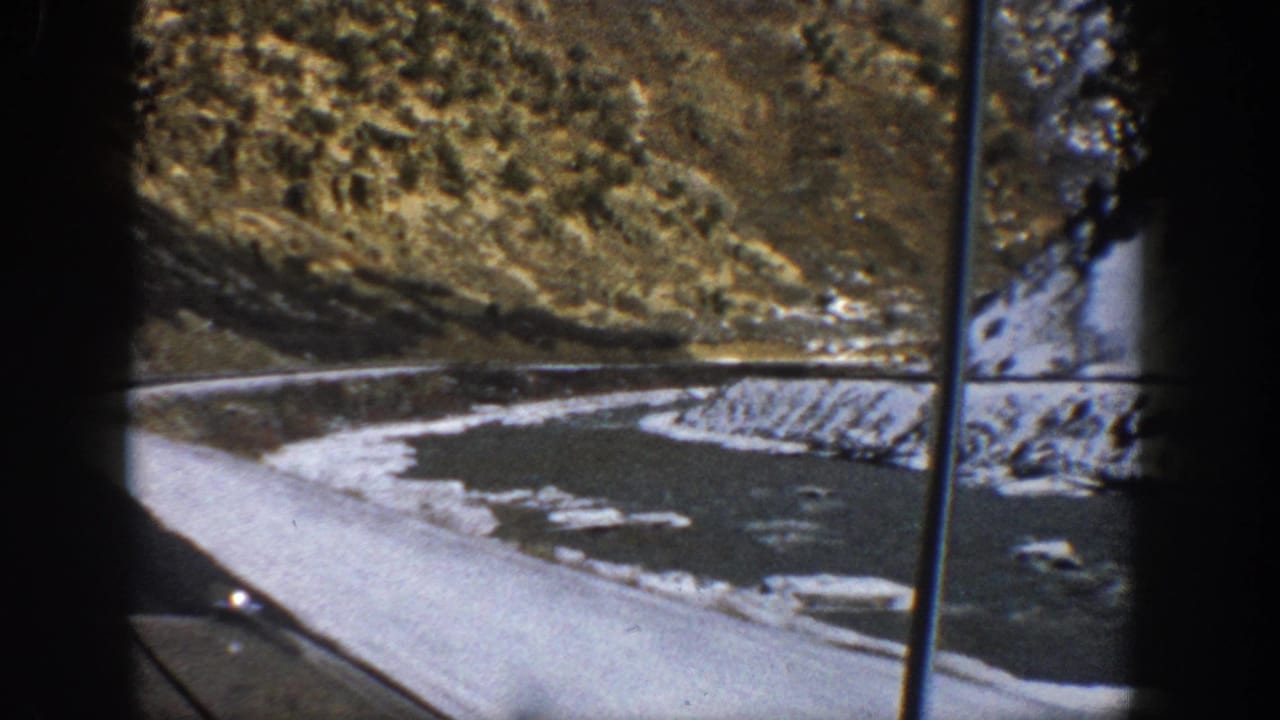 1961 Aspen-area home-movie view of a snowy road edge and river from inside a moving car.