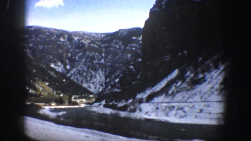 Aspen-area 1961 car-window view of a river, snowy banks, and shadowed Rocky Mountain slopes.