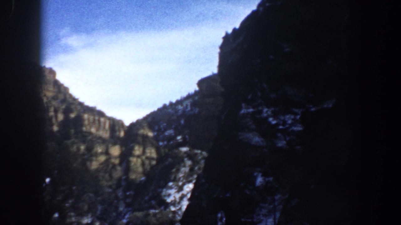 Steep shadowed canyon walls with snow patches and a strip of blue sky above.