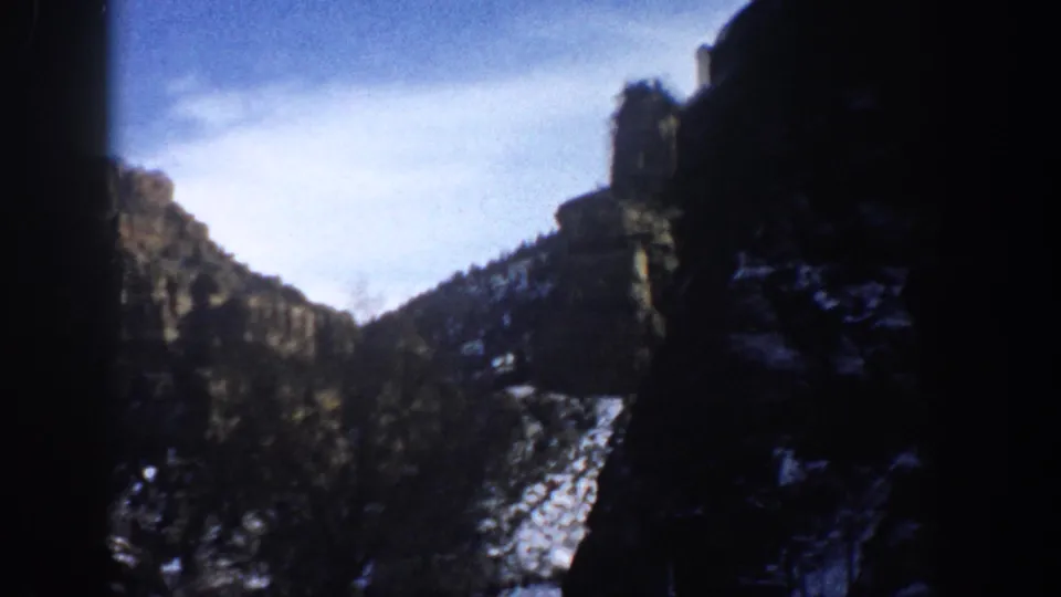 1961 Aspen, Colorado 8mm view of rugged rock walls, winter snow remnants, and a partly obstructed scenic frame.