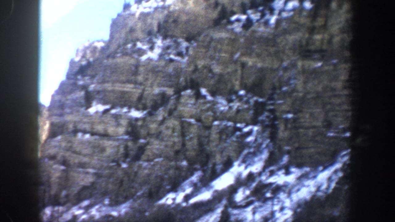 Rocky canyon walls with snow patches and a bright gap of sky.