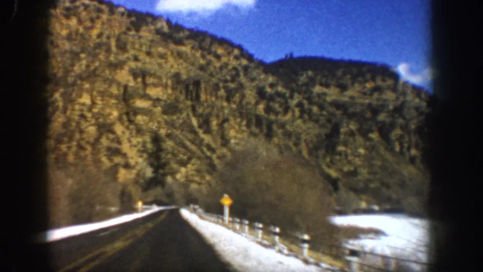 1961 8mm travel frame showing a snow-lined road through rugged terrain near Aspen, Colorado.