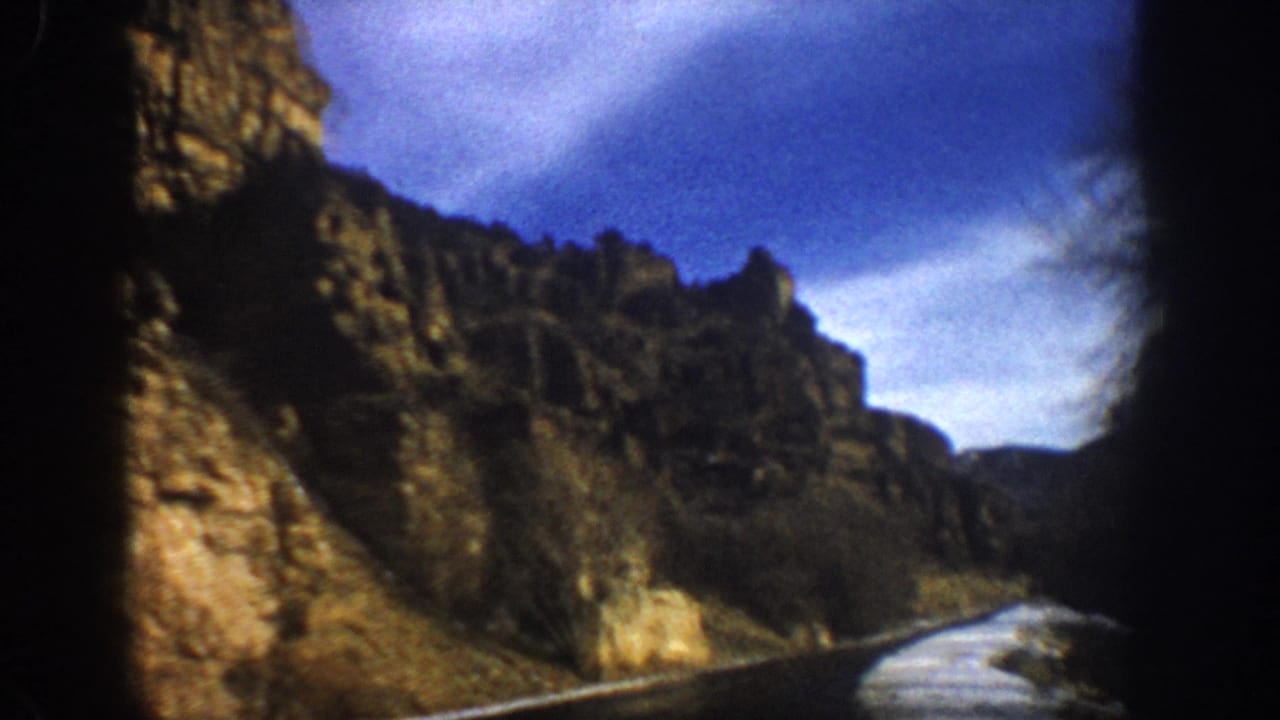 Canyon road curves past rocky cliffs with snow along the roadside.