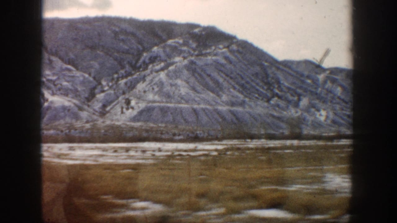 1961 Aspen, Colorado 8mm frame showing layered winter hills and open valley ground through dark window or film-frame edges.