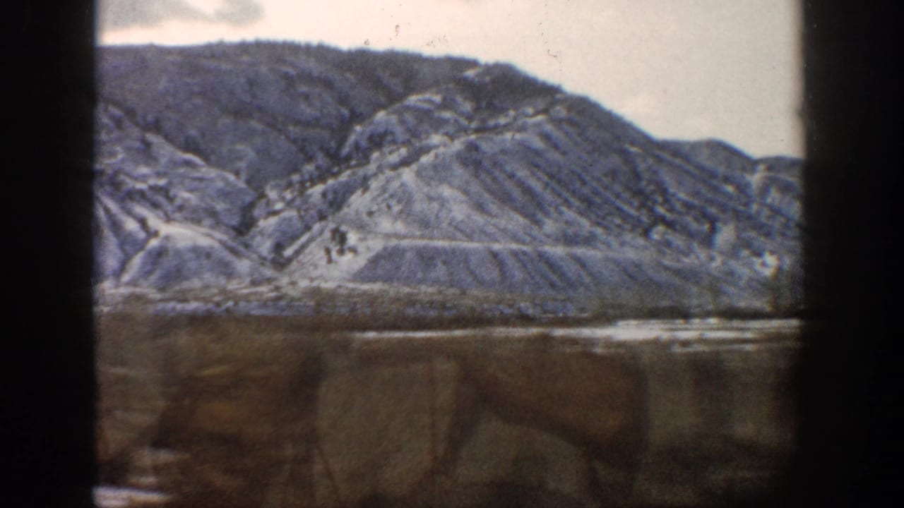 1961 Aspen, Colorado 8mm view of a rugged snow-streaked mountain slope and muted winter foreground from a vehicle.