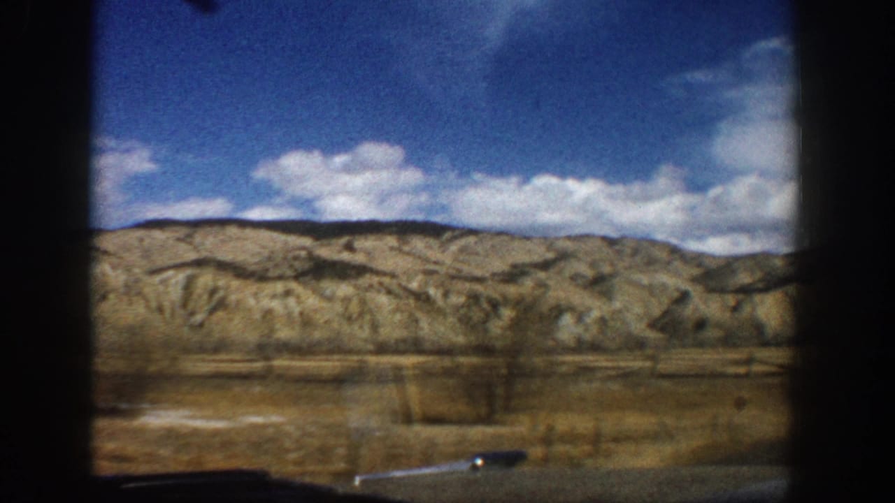 Open plain and layered hills beneath blue sky with scattered clouds.
