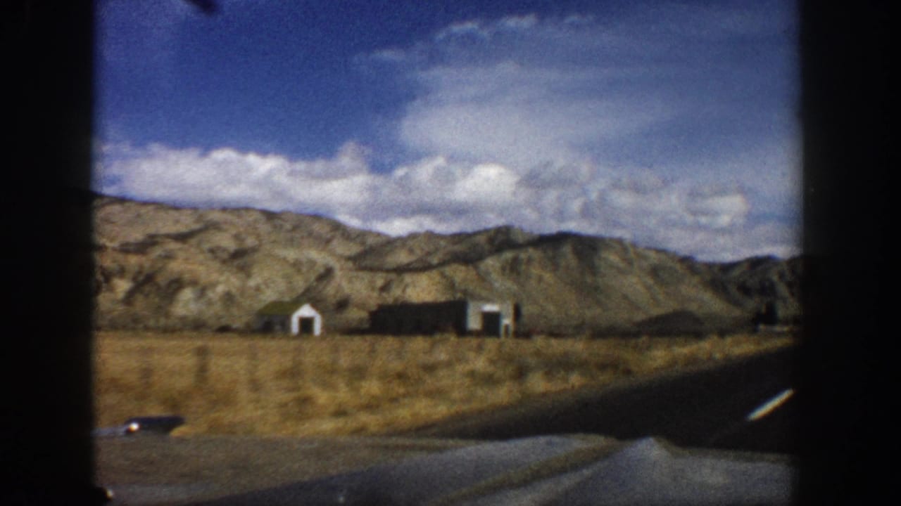 Small roadside buildings and dry mountains beside a paved highway.
