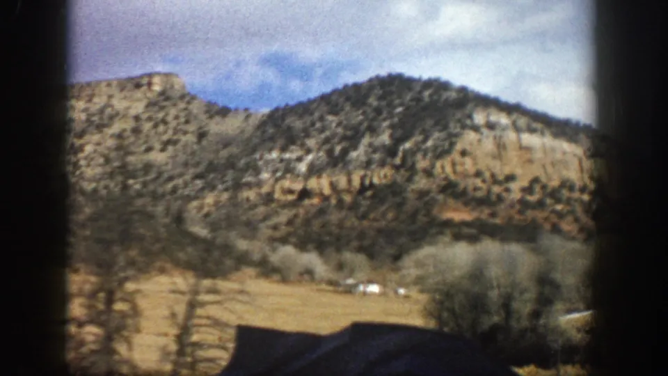 A 1961 Aspen, Colorado roadside landscape with scrubby hills, dry grass, bare trees, and dark car-window framing.