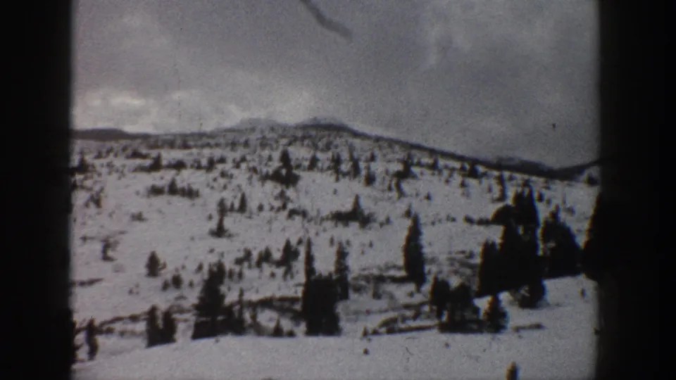 1961 Aspen, Colorado winter landscape with scattered evergreens across a snowy hillside and a dark 8mm frame division at left.