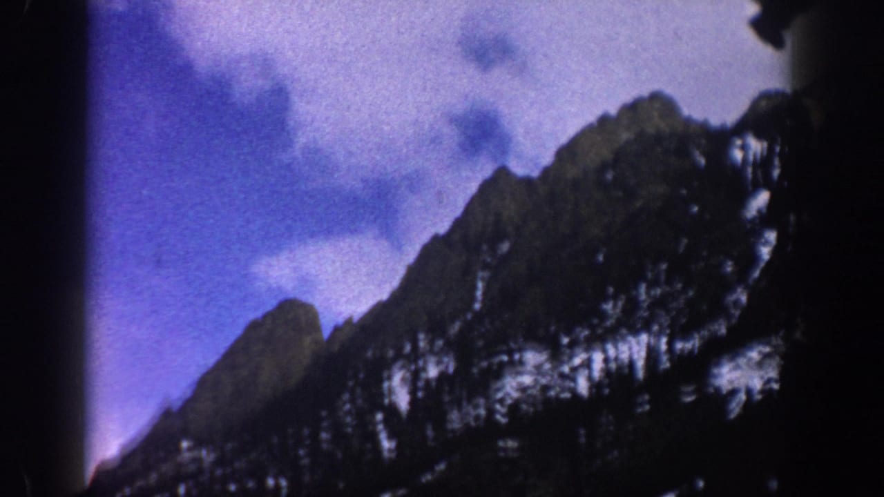 Snow-dusted mountain ridge rising beneath blue-purple clouds.