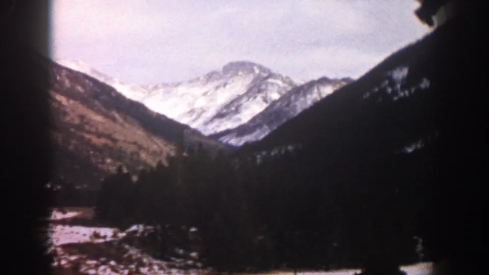 1961 Aspen-area 8mm frame showing snow-capped mountains and a dark valley viewed from inside or near a moving car.