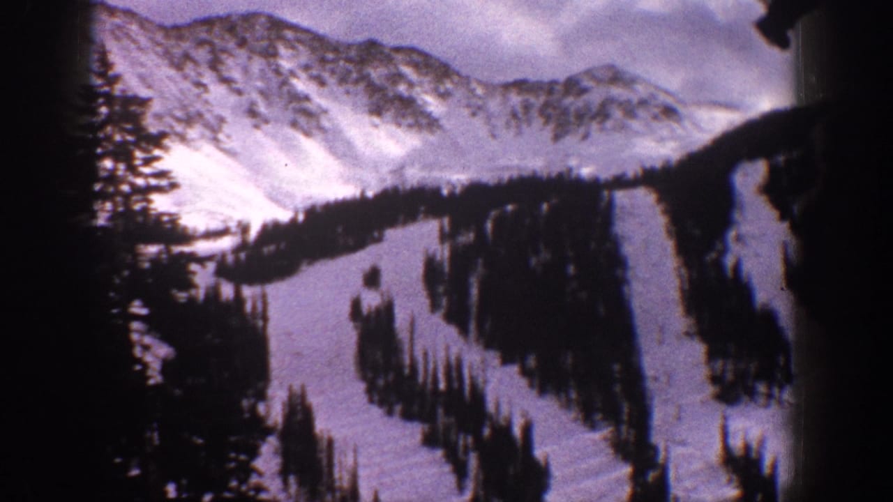 Aspen-area 8mm frame from 1961 with snowbound ridges, evergreen-lined ski runs, and dark foreground obstruction from the filming position.