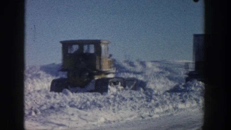 1961 Aspen 8mm frame showing a tracked snow-clearing machine partly silhouetted against high snowbanks.