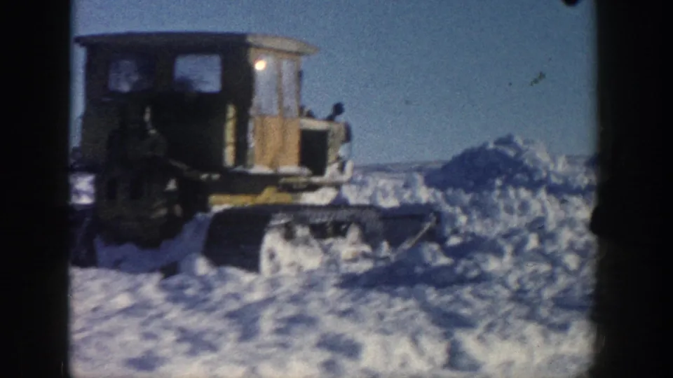 Close 8mm view of a tracked snow-clearing vehicle in Aspen, with a shadowed operator area and heavy snow around it.
