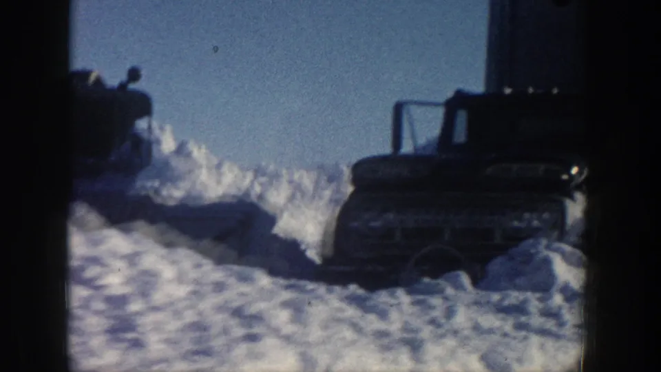 1961 Aspen winter frame showing a rugged vehicle near deep snowdrifts, with another machine shape at left.