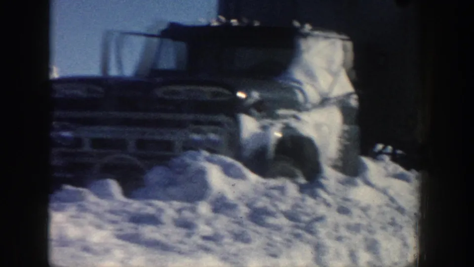 1961 Aspen, Colorado 8mm frame showing a truck cab heavily coated in snow and partially buried near a high snowbank.