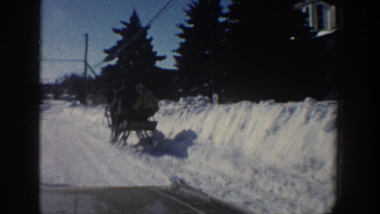 A horse-drawn sleigh with visible passengers passes along a snowy Aspen road in the 1961 8mm home-movie footage.