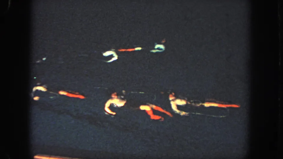 Multiple swimmers form a horizontal pattern in dark pool water during the 1951 Atlanta synchronized routine.